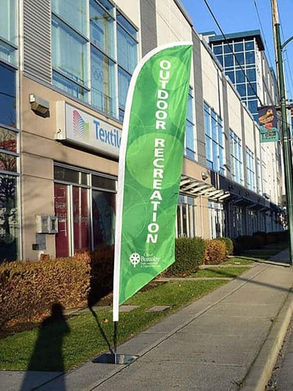 Drapeau plume blade déployé devant une devanture sur trottoir
